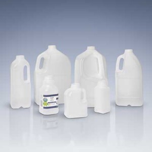 Assorted white plastic jugs of varying sizes arranged on a reflective surface, likely liquid containers or detergent bottles