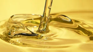 Golden liquid splashing and swirling on a smooth surface, resembling oil or syrup in motion