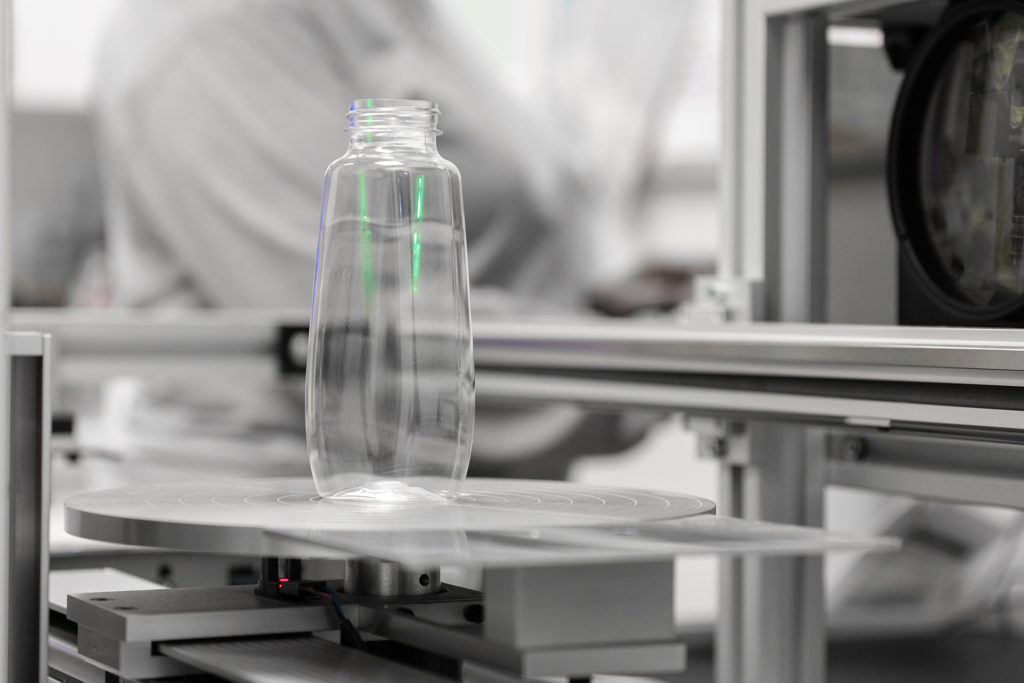 Photo of clear bottle on quality assurance machine