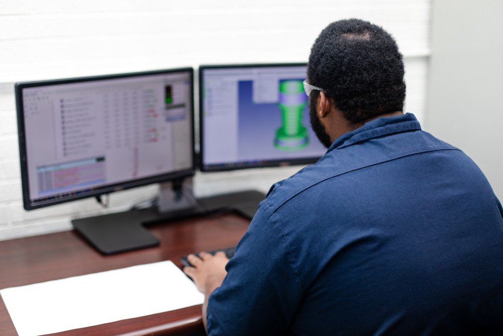 Photo of man looking at two computer screens