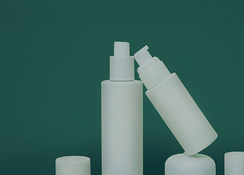 Three white spray bottles on a dark green background, with one bottle tilted radially toward the others.