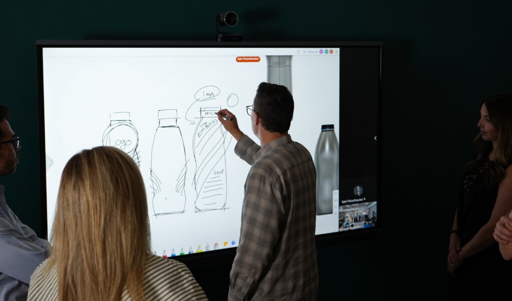 Packaging concept designer showing clients bottle drawings on a light board.